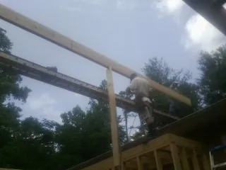 Carpenter setting a ridge beam over a new addition frame — Ice Dam Removal by Roofing Brothers in Ramer