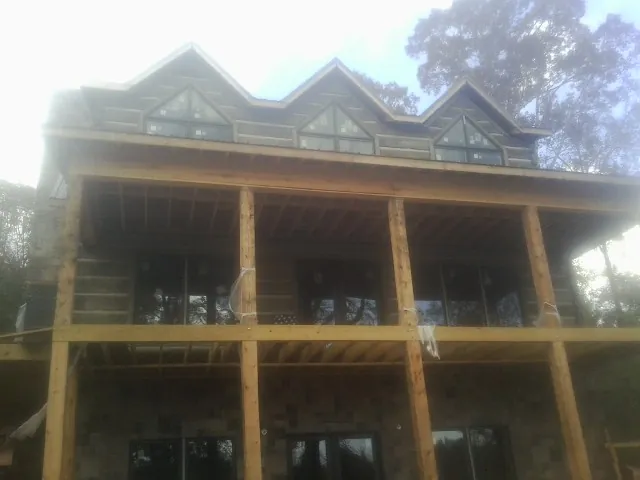 Dormers and porch framing on a large log home under construction — Roof Coating work by our crew in Ramer