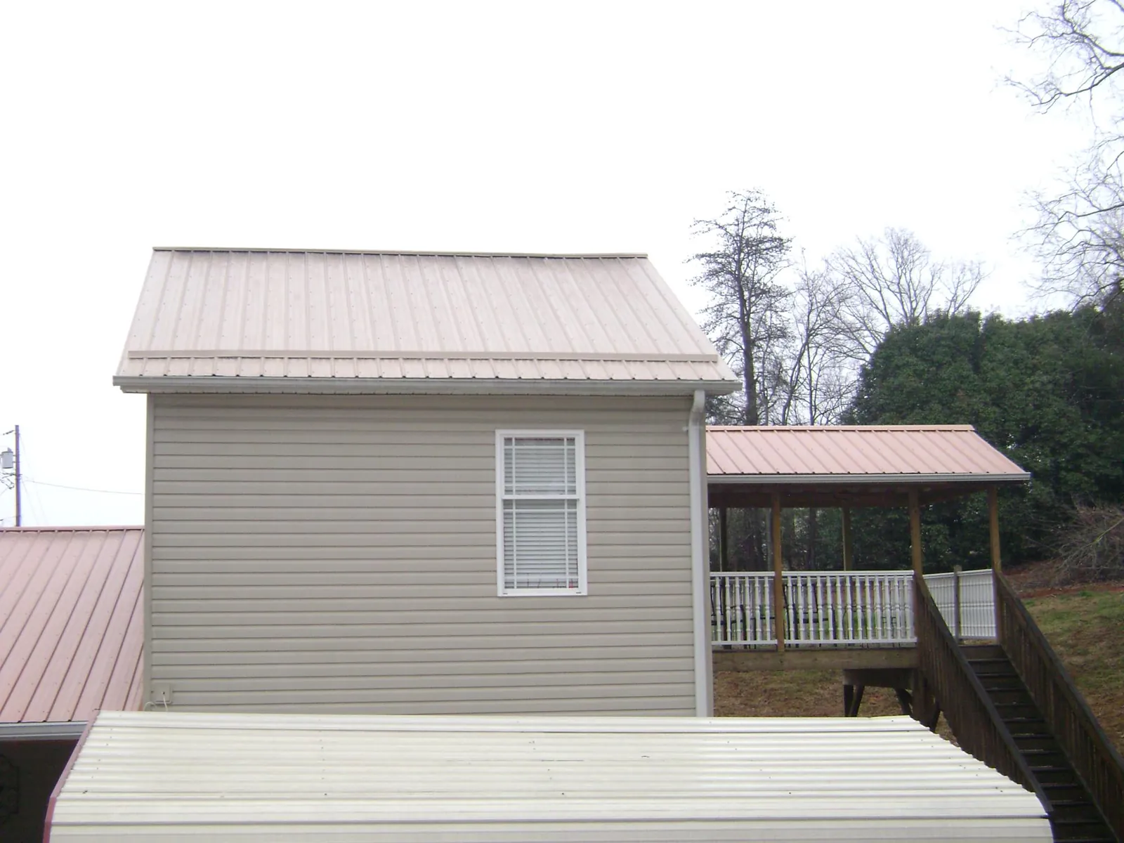 Tan metal roofs on a two story addition and attached porch, from a Roof Replacement job in Ramer